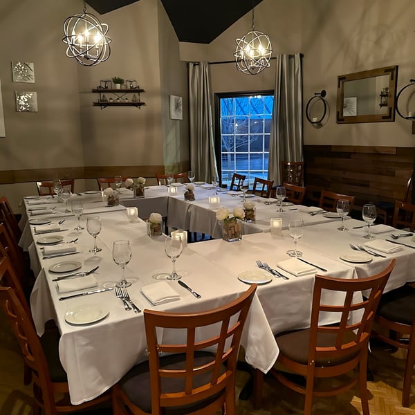 A private dining room at Paradiso's Restaurant with a U-shaped table set for a formal Italian meal.