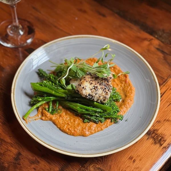 A Paradiso's Restaurant dish with sesame-crusted fish, broccolini, and red sauce on a gray plate.
