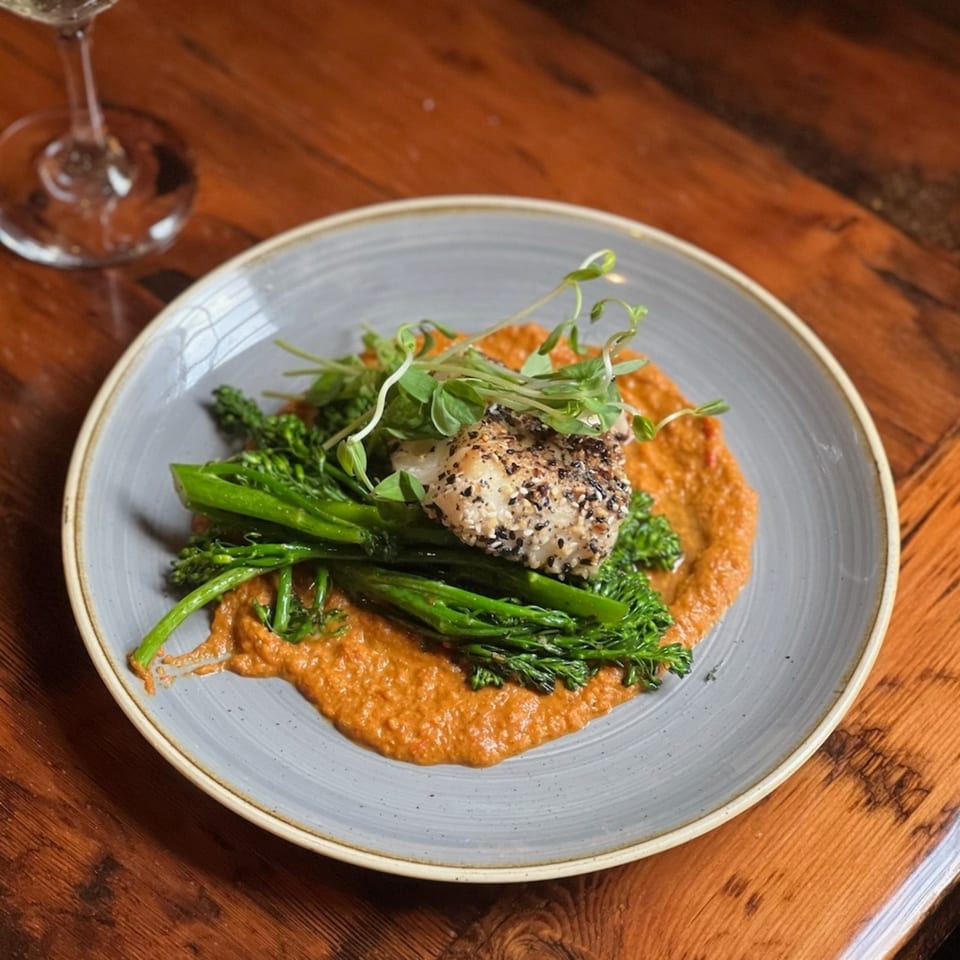 A Paradiso's Restaurant dish with sesame-crusted fish, broccolini, and red sauce on a gray plate.
