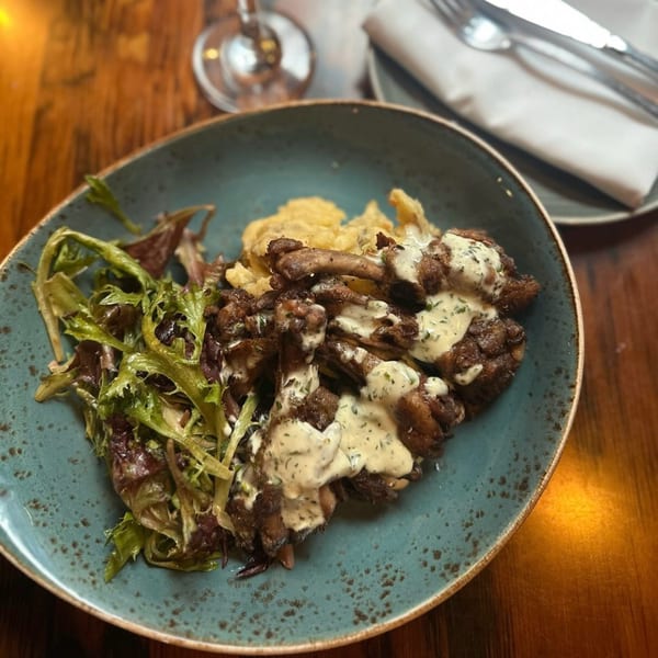 Paradiso's Italian dish with fried mushrooms, creamy sauce, and a side salad on a blue plate.